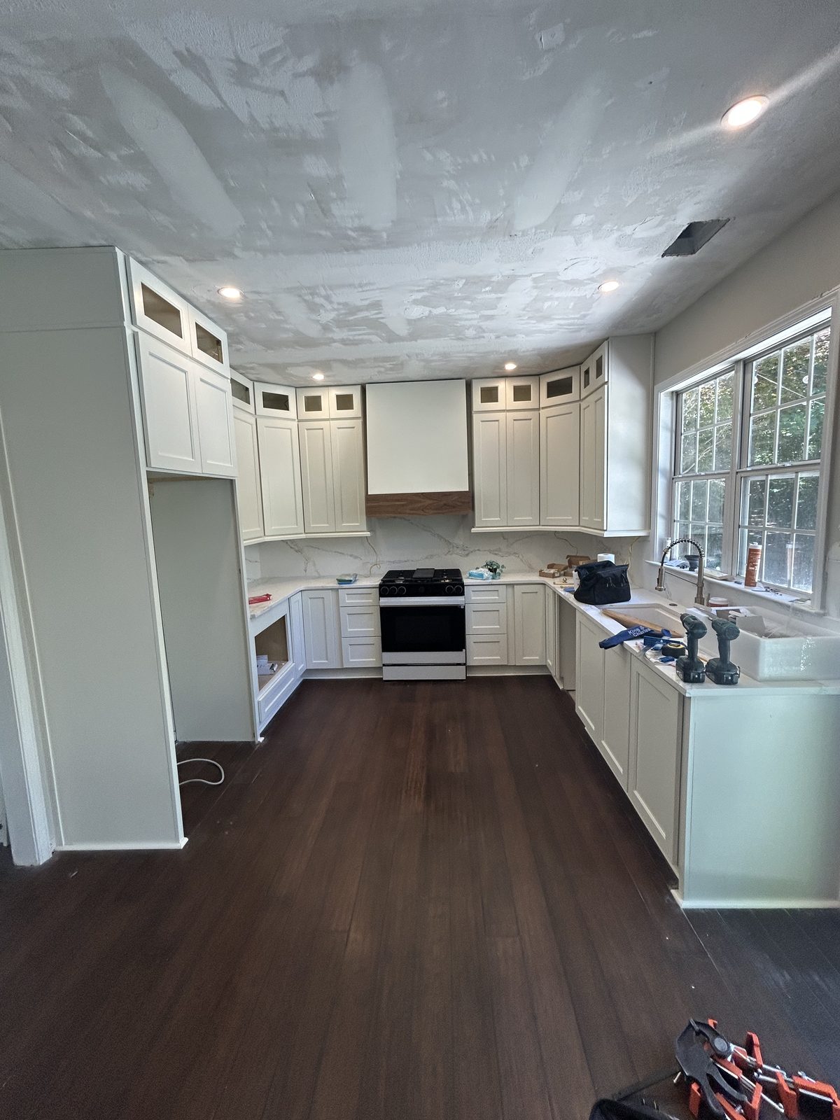 After: new white shaker cabinets, quartz countertops, and a full-height quartz backsplash behind the range