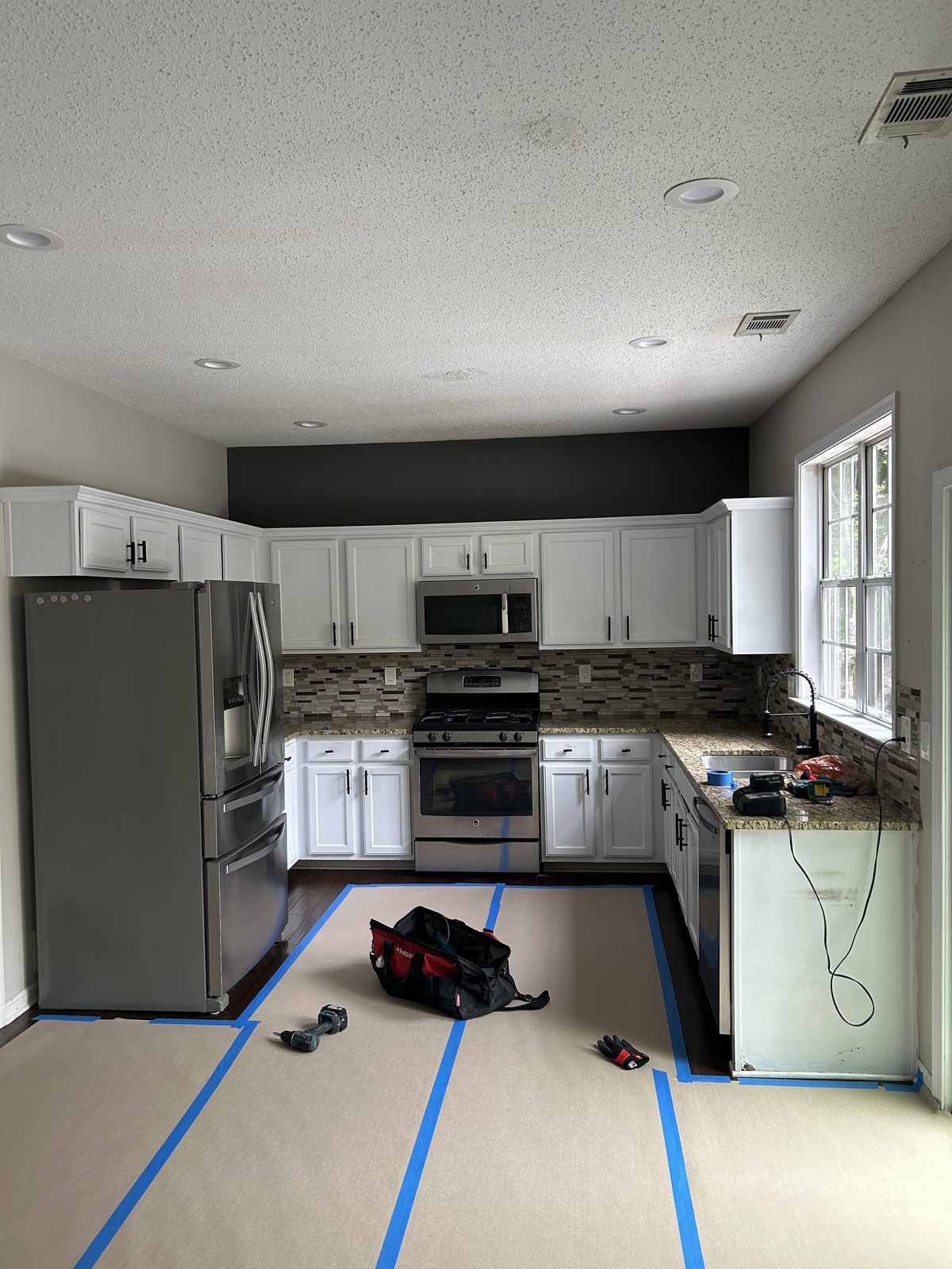 Before: the original kitchen with dated raised-panel cabinets and a mosaic tile backsplash