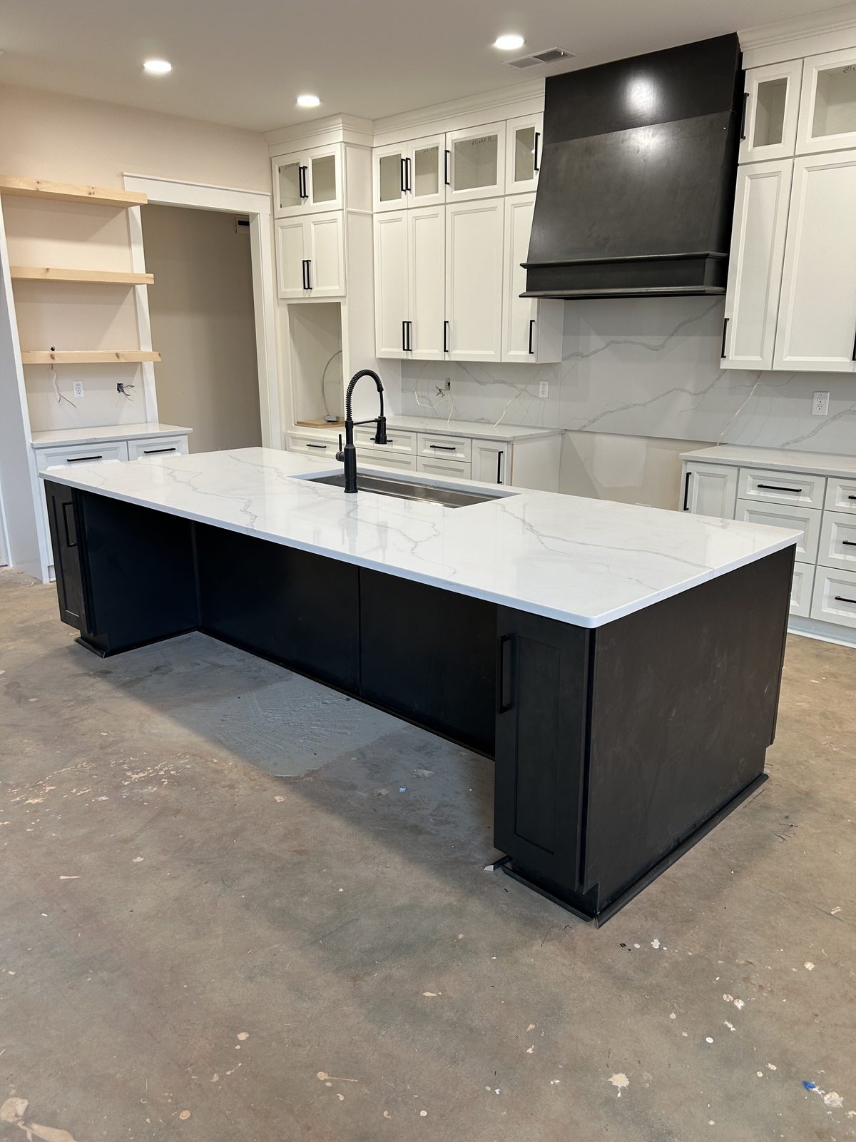 Two-tone kitchen with pearl white perimeter cabinets, glass stack uppers, and a volcanic grey island with a quartz waterfall countertop