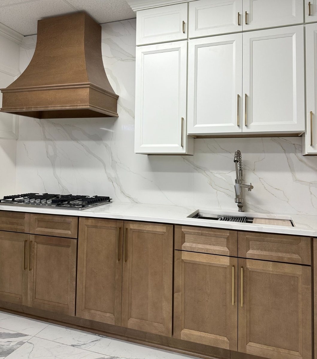 Sink wall with Lanier Tawny base cabinets under a marble-look countertop and Pearl White upper cabinets