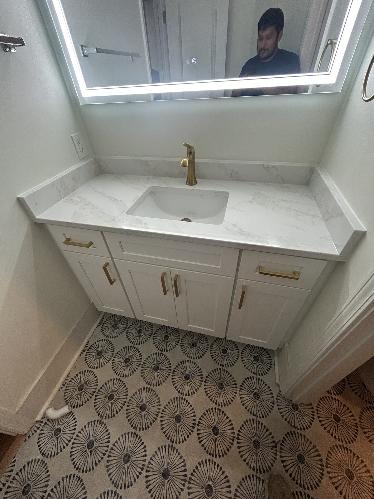 After: a shaker white vanity with a white quartz countertop and backsplash, undermount sink, and brushed-gold handles